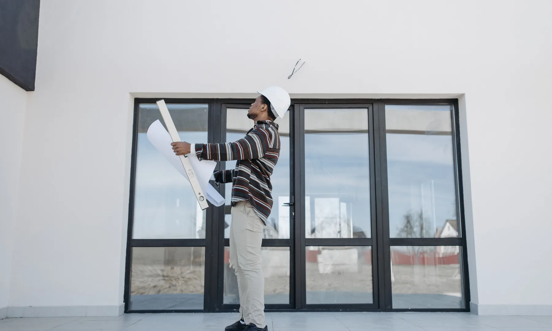 Architect and buyer reviewing plans beside a building under construction